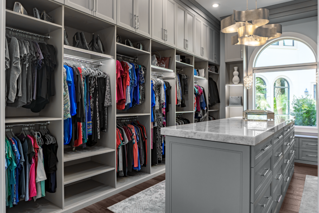 Photo of a women&#039;s closet with lots of hanging clothes and a island table top in the center