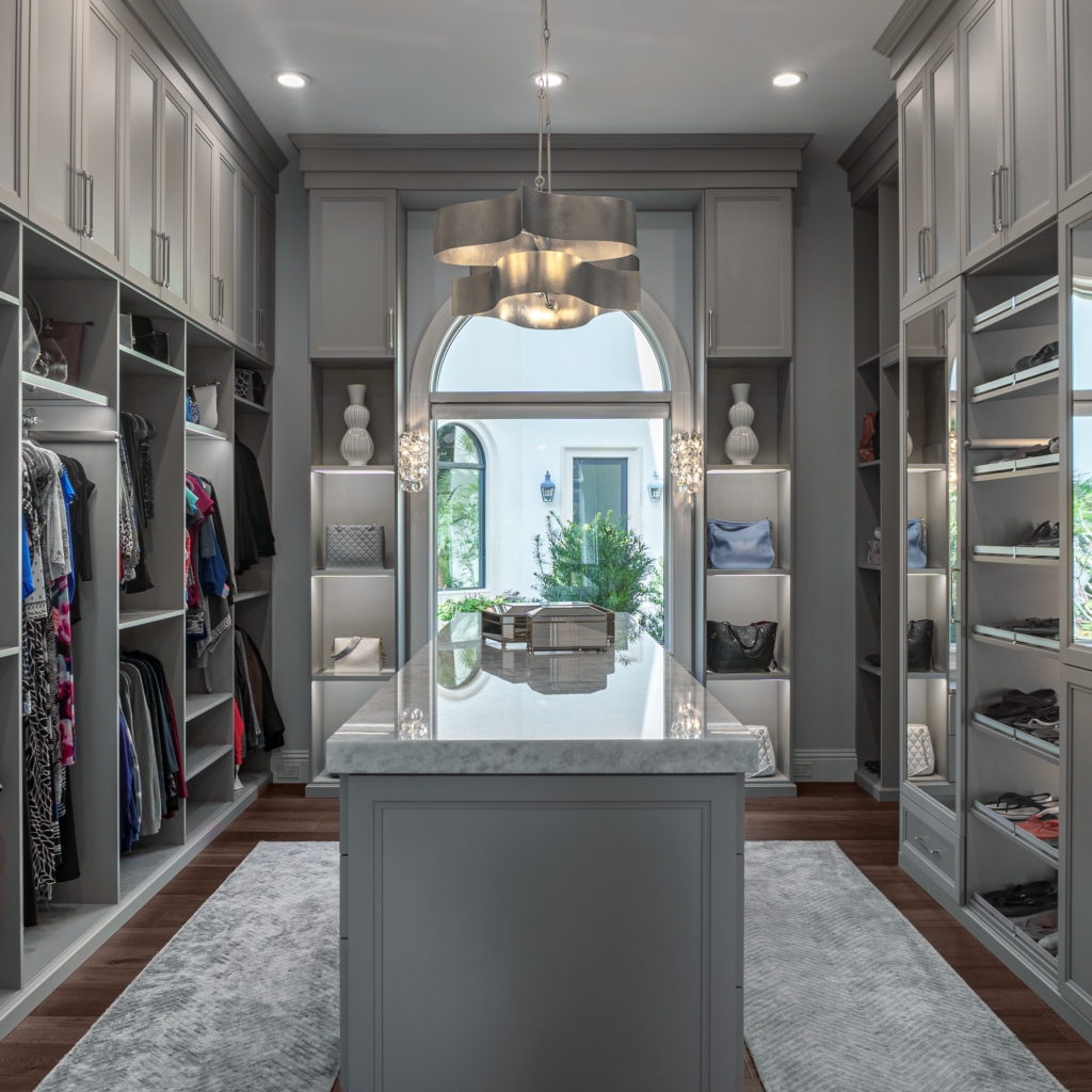 Photo of a women&#039;s closet with lots of hanging clothes and a island table top in the center