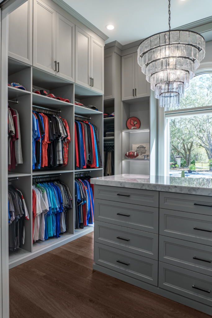 Photo of a men&#039;s closet with lots of hanging clothes and a island table top in the center