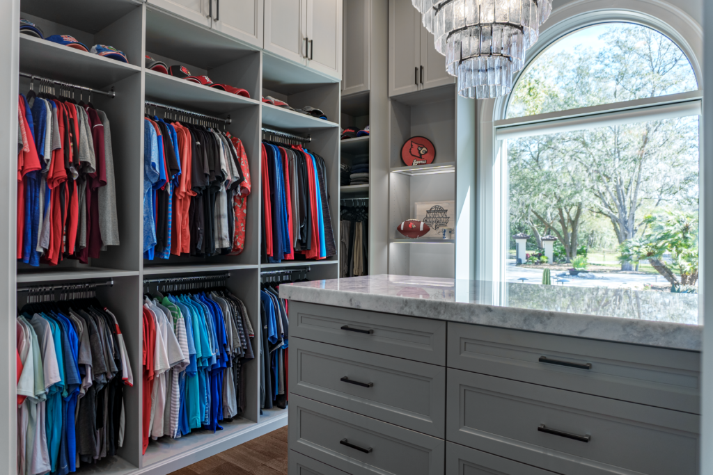 Photo of a men&#039;s closet with lots of hanging clothes and a island table top in the center