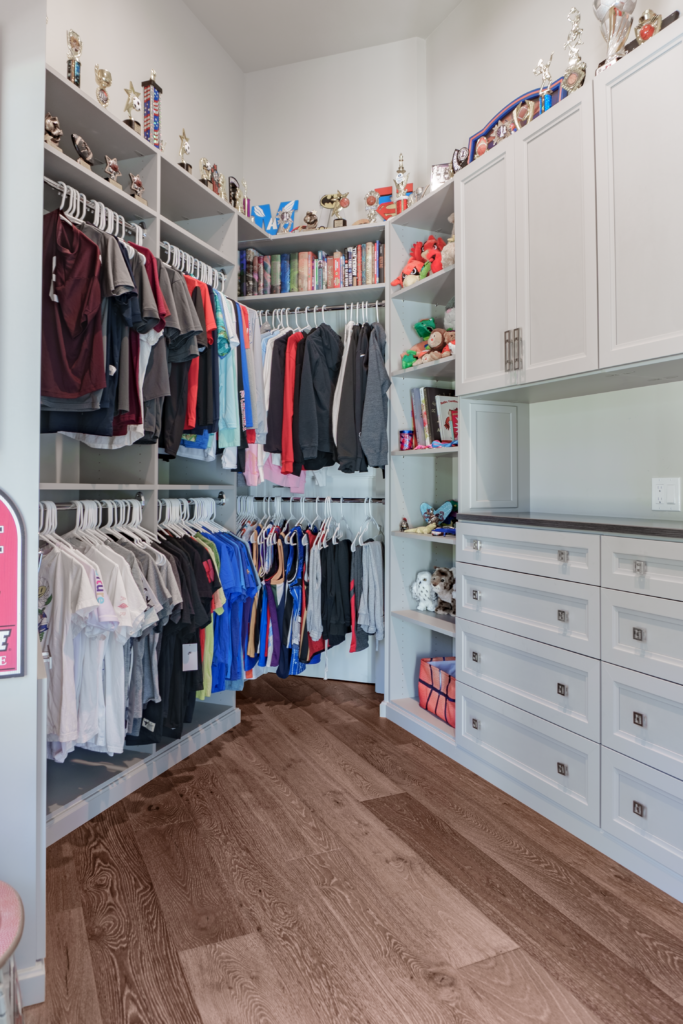 Photo of a boys closet with clothes hung to the left and drawers to the right