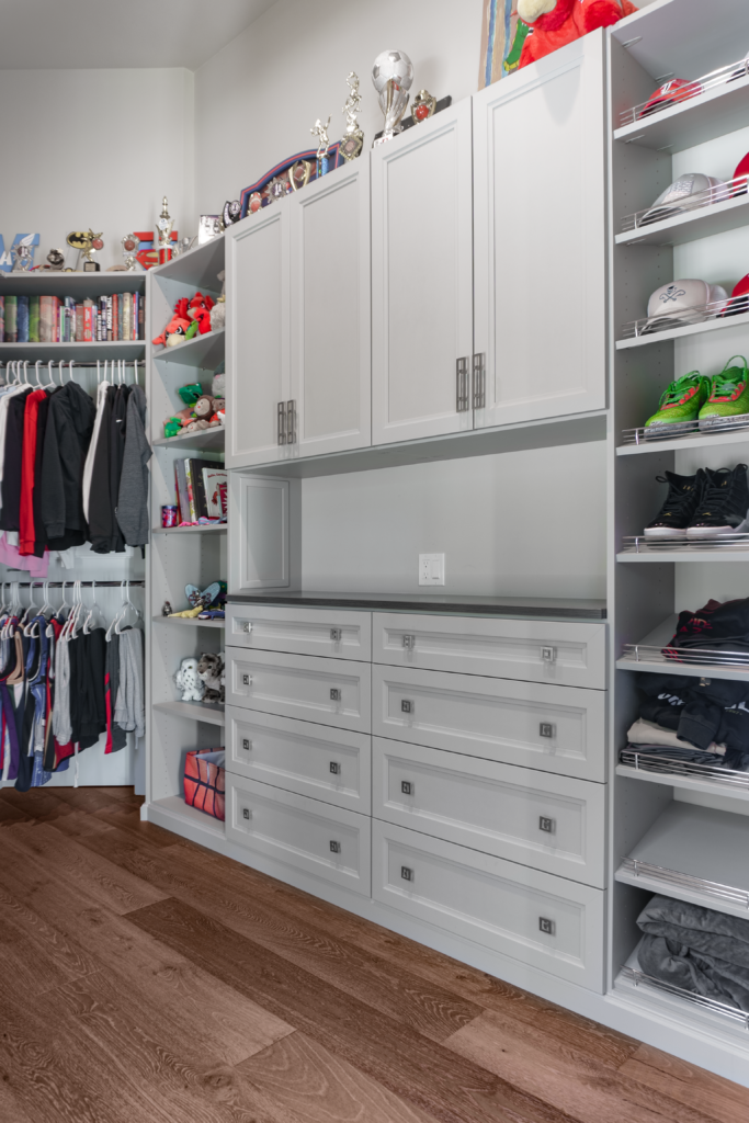 Photo of a boys closet with clothes hung to the left and drawers to the right